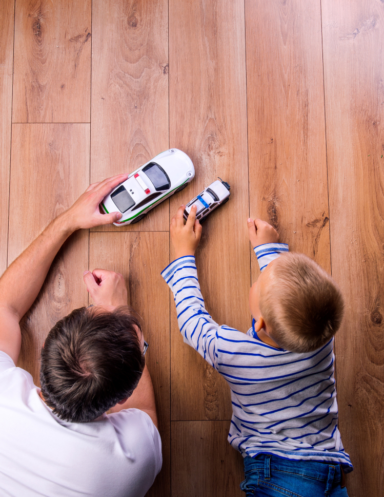 Kids playing cars on hardwood floor.  